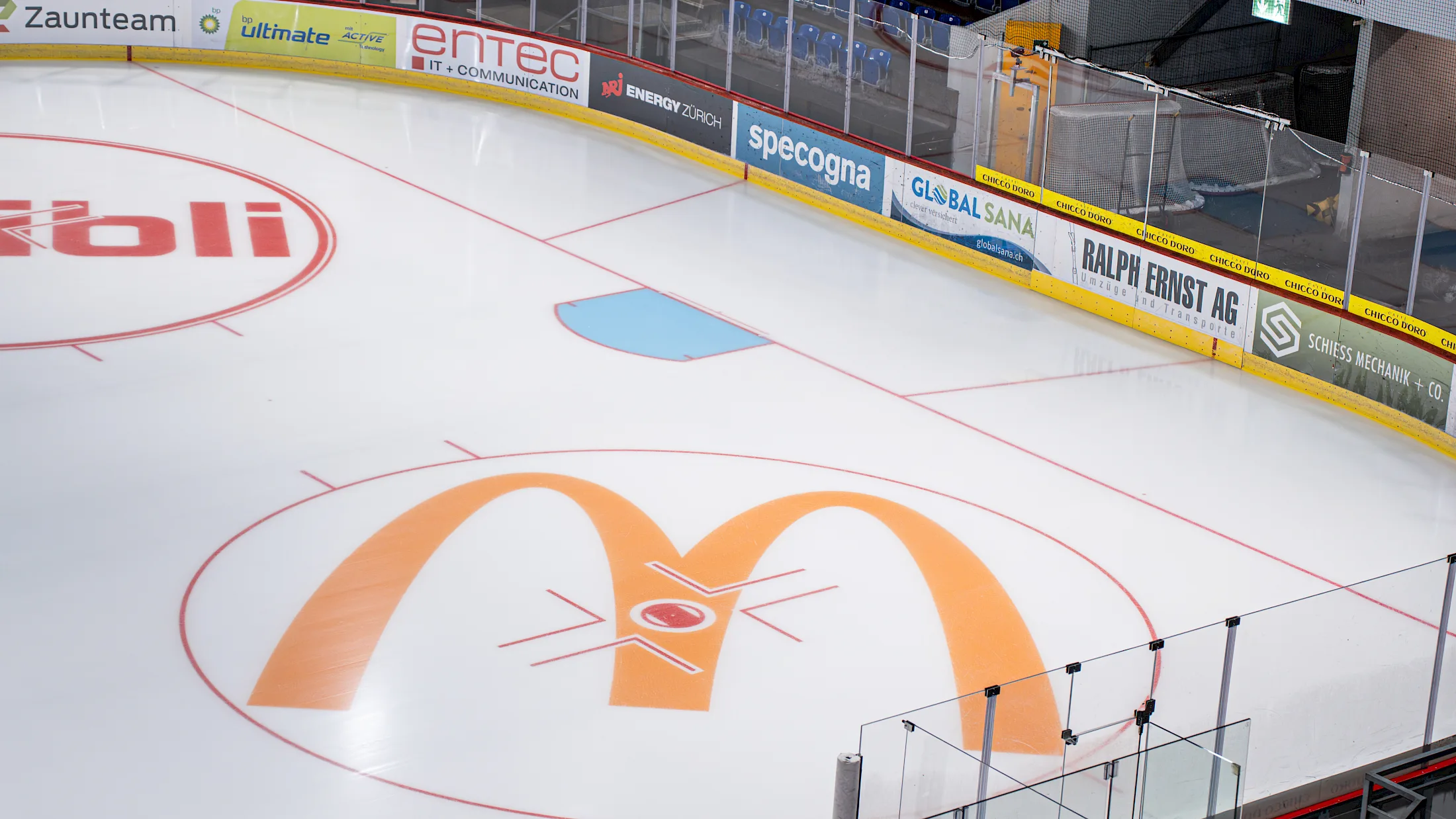 Leeres Eisfeld der SWISS Arena mit Bandenwerbung und blauen Zuschauerreihen