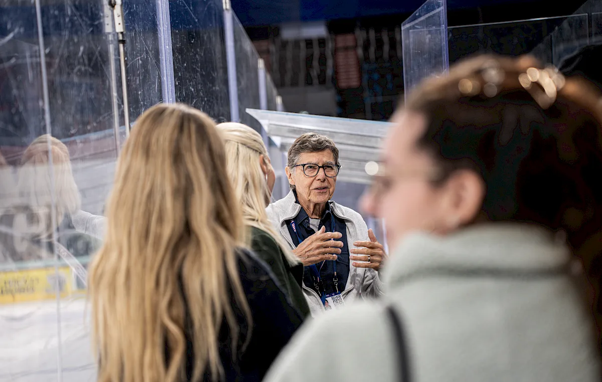Guide erkl&auml;rt Besucherinnen bei einer Stadionf&uuml;hrung Details direkt am Eisfeld