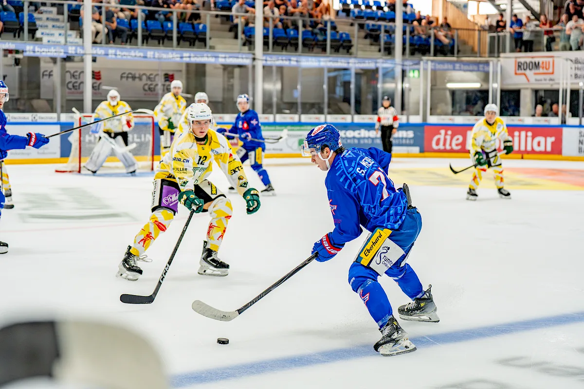 Simon Meier mit Nummer 71 im blauen Trikot am Puck w&auml;hrend eines Spiels gegen ein gelb gekleidetes Team