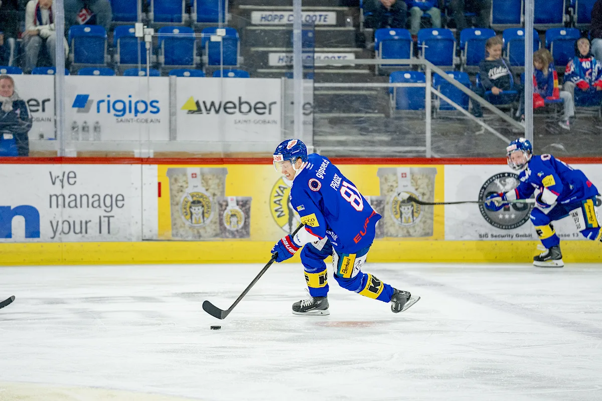 Raphael Prassl im blauen EHC Kloten-Dress mit Nummer 81 f&uuml;hrt den Puck &uuml;ber das Eis