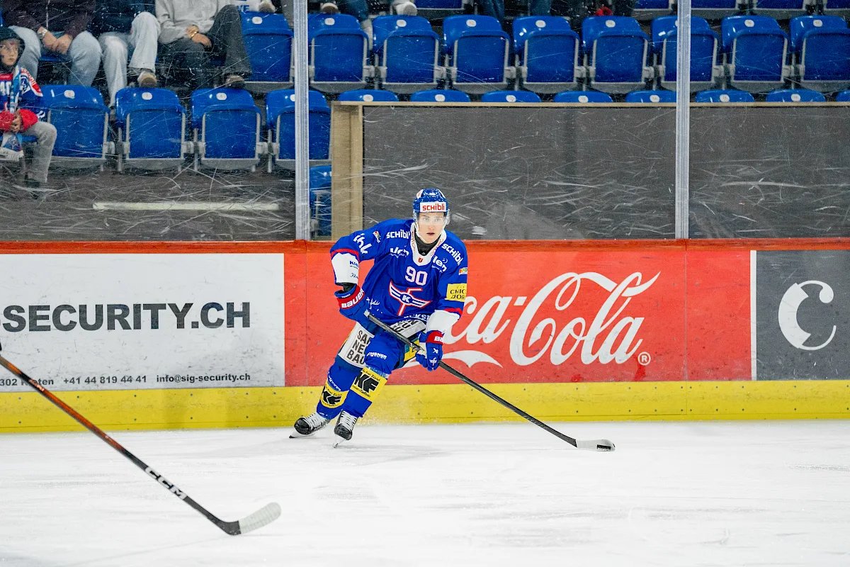 Petteri Puhakka im blauen EHC-Kloten-Trikot mit Nummer 90 f&uuml;hrt den Puck auf dem Eis
