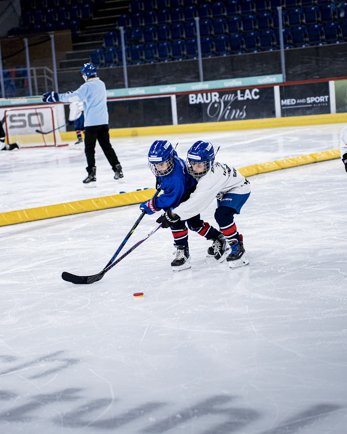 Trainer erklärt Kindern der Hockeyschule eine Übung auf dem Eis in der Arena
