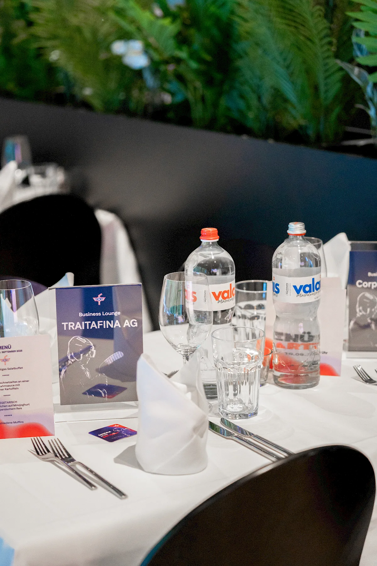 Gedeckter Tisch in der EHC-K Business Lounge mit Namenskarte, Men&uuml; und Getr&auml;nken