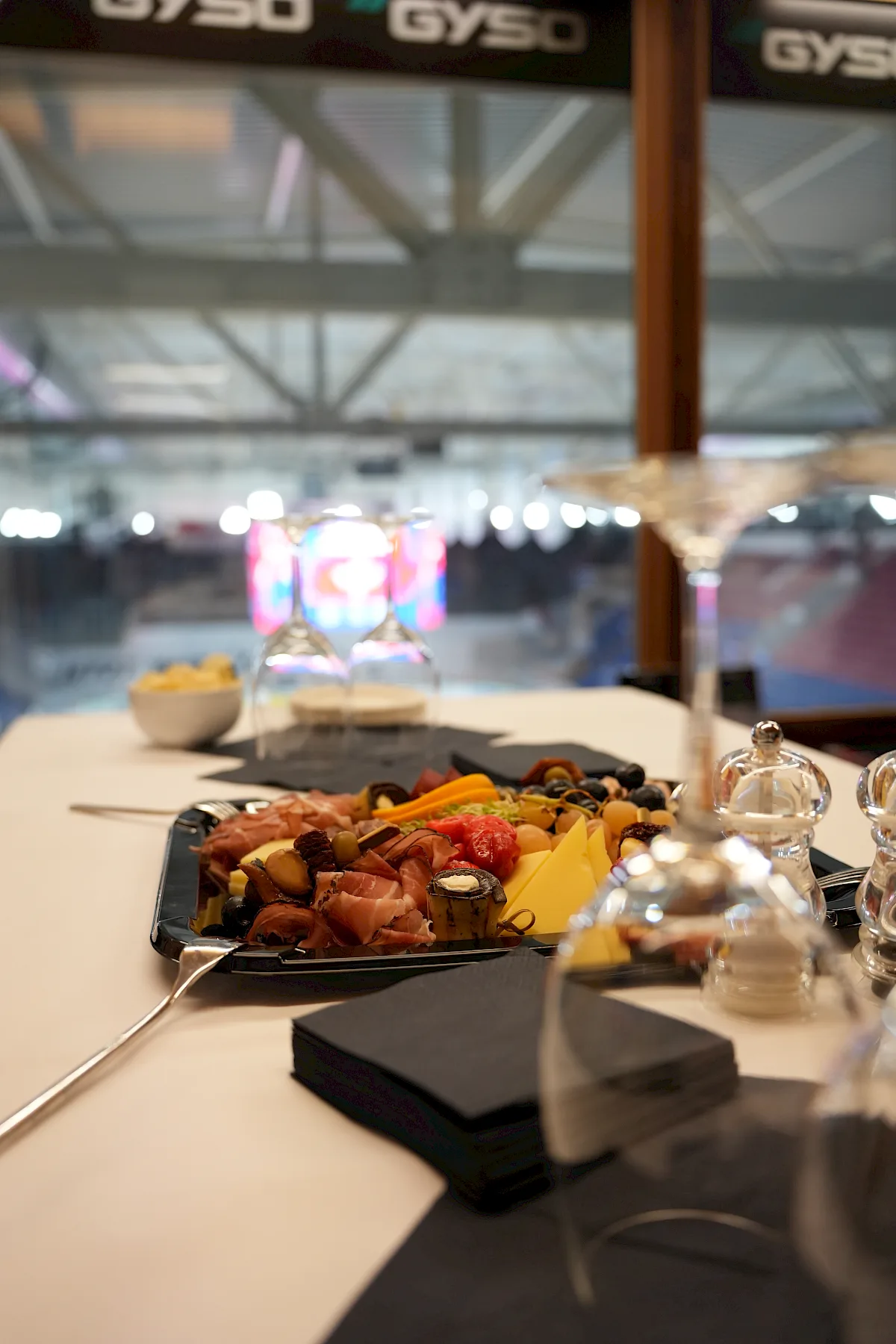 Antipasti-Platte mit Aufschnitt und K&auml;se im Gyso-Slot, im Hintergrund die Eisfl&auml;che der SWISS Arena