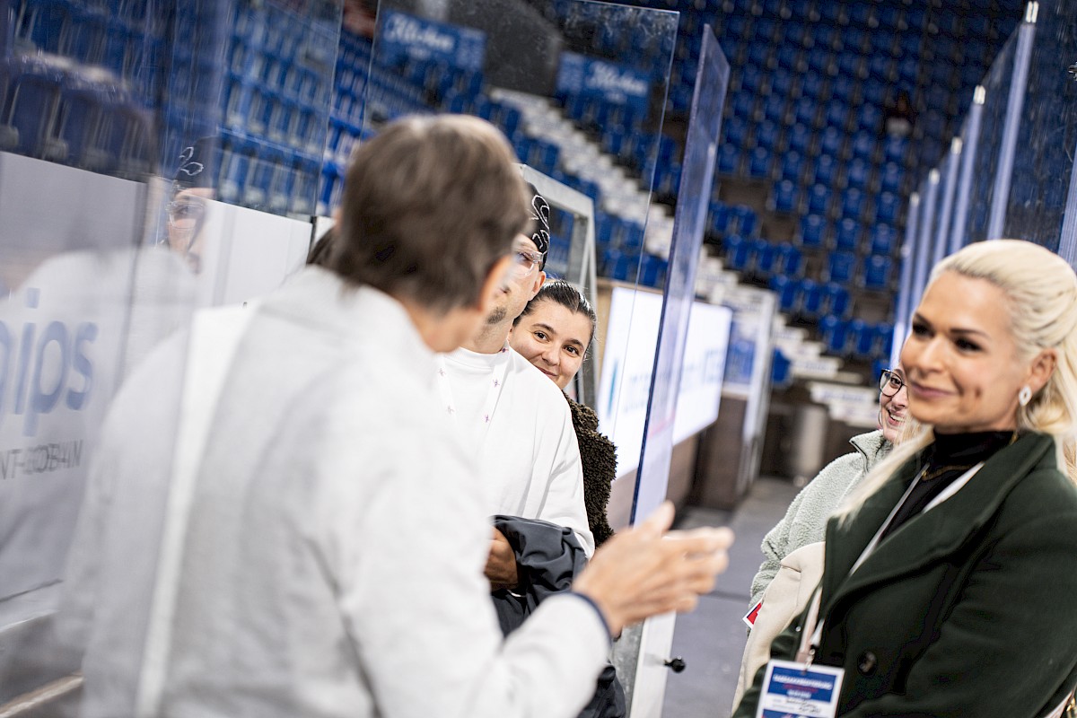 G&auml;ste unterhalten sich hinter der Plexiglasscheibe an der Bande in der SWISS Arena