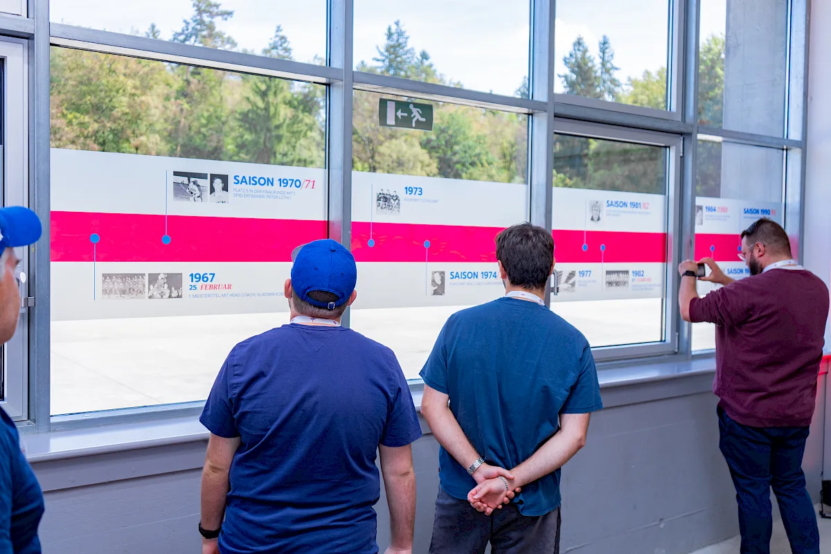 Besucher betrachten eine Zeitleiste mit Club-Saisons an einem Fenster der SWISS Arena