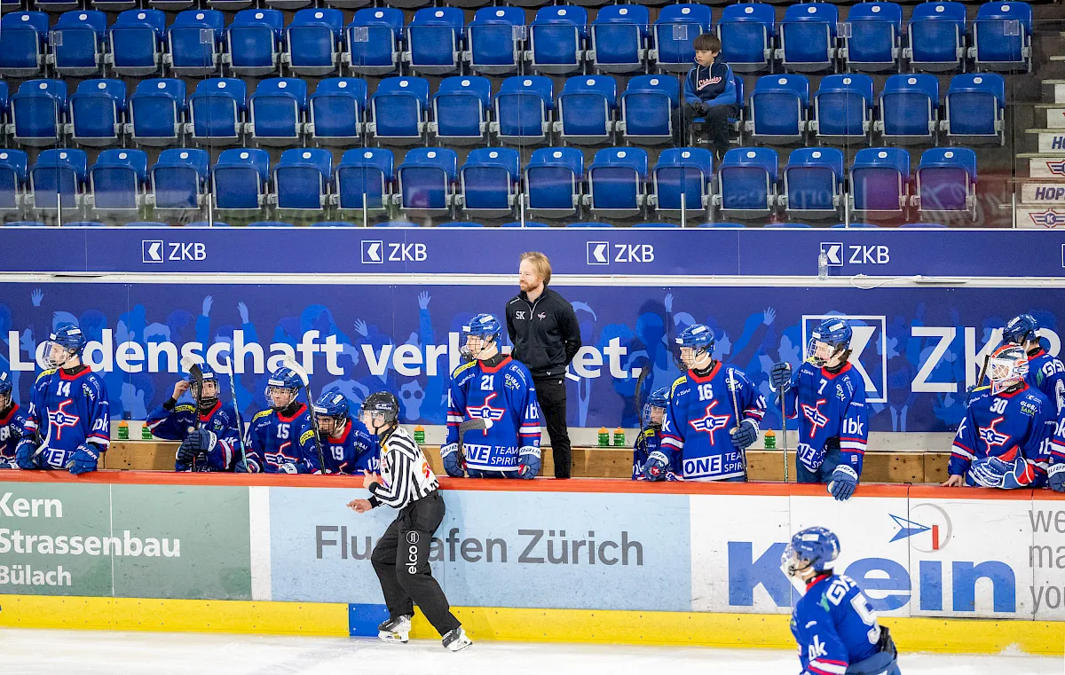 Nachwuchsspieler des EHC Kloten in blauen Trikots an der Bande feiern nach dem Spiel